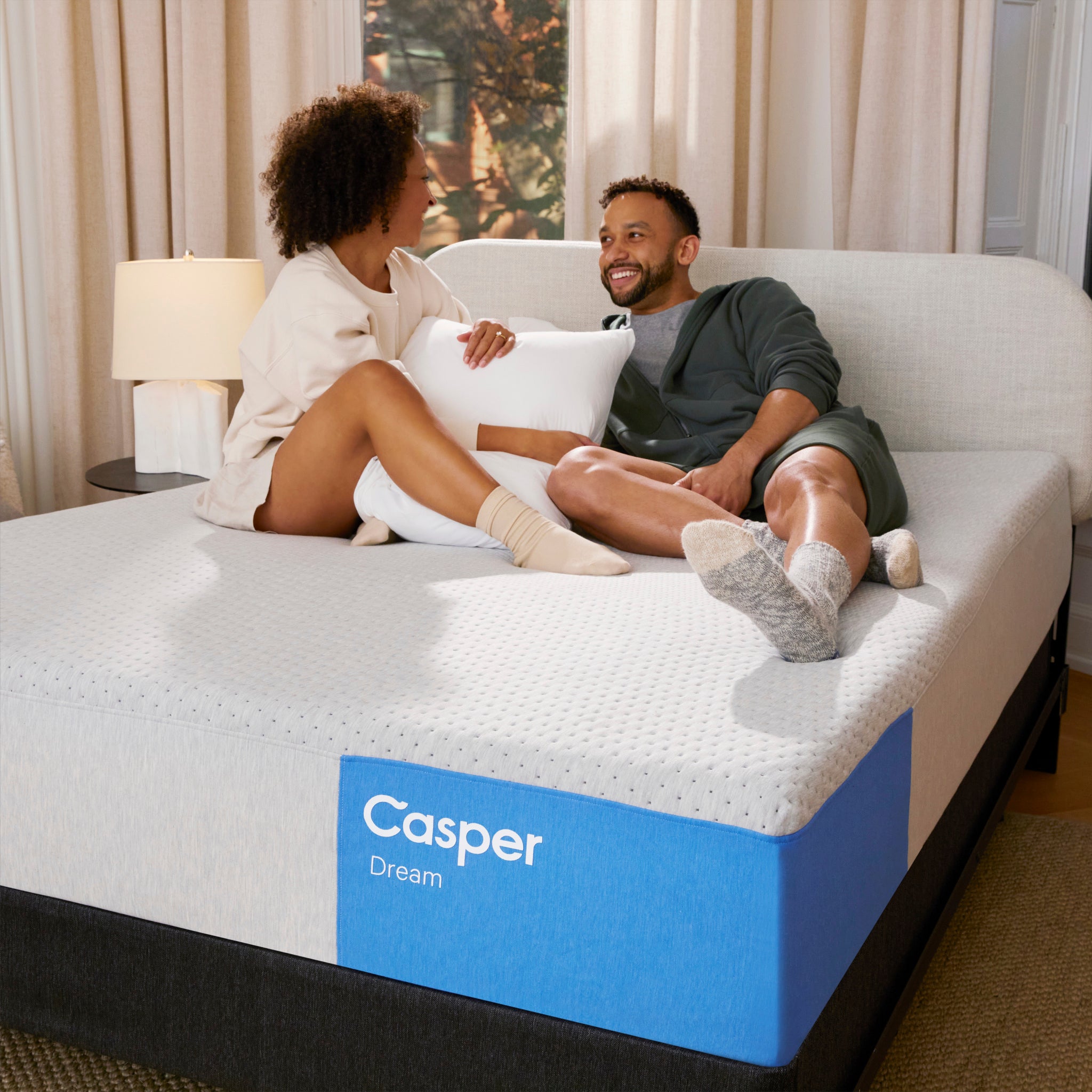 Couple sitting on Dream 12” Mattress by Casper | Hybrid design with ergonomic Zoned Support